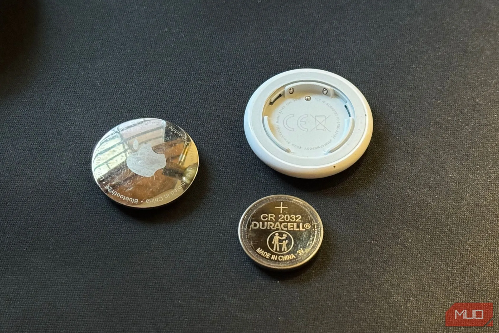 AirTag đã tháo rời và viên pin CR2032 trên nền đen