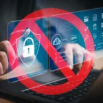 Bàn tay gõ laptop với dấu cấm màu đỏ đè lên các biểu tượng bảo mật, minh họa rủi ro từ tiện ích mở rộng trình duyệt độc hại.