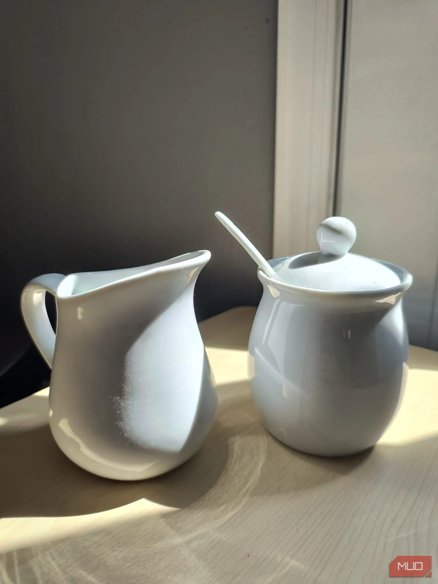 Bộ đựng đường và kem bằng sứ trắng dưới ánh nắng trực tiếp với HDR bật
