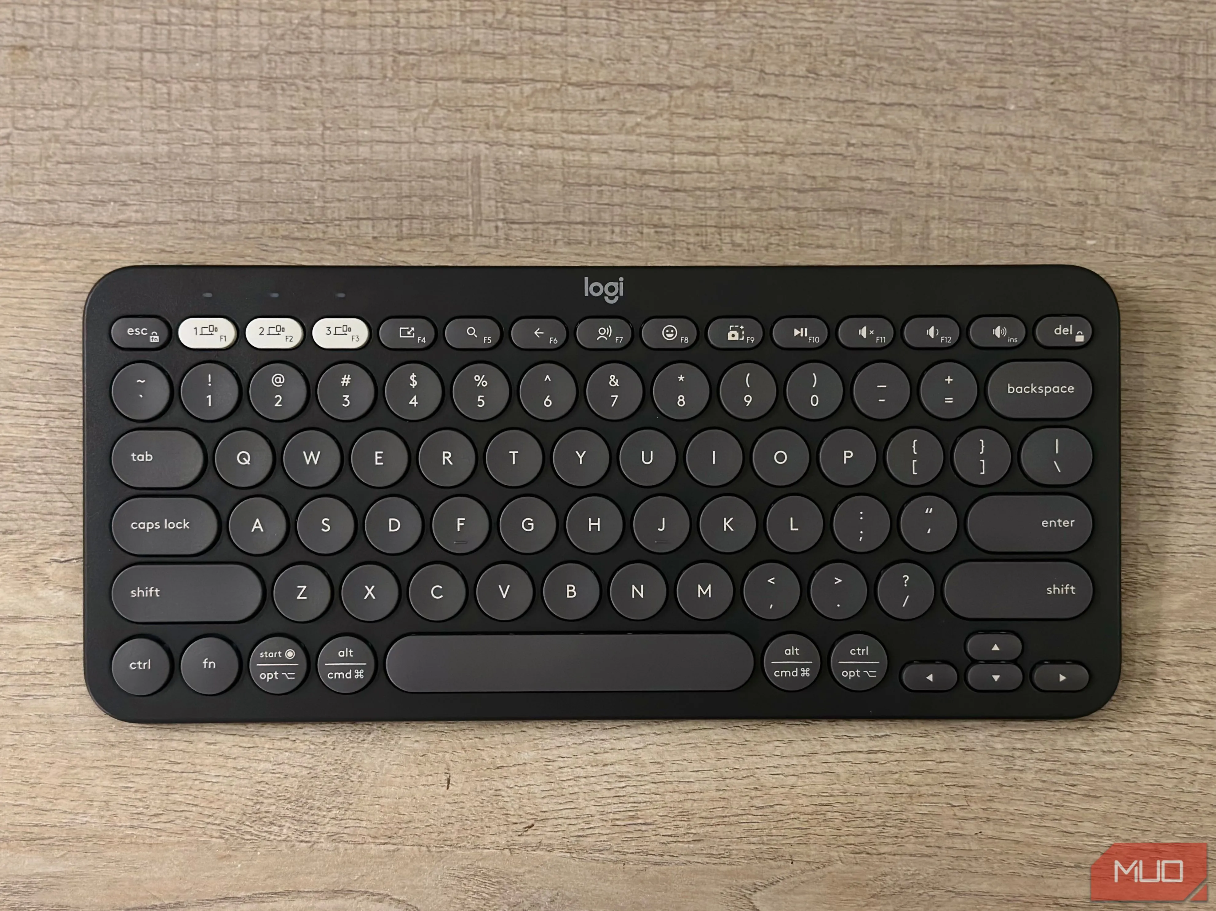 Cận cảnh bàn phím không dây Logitech Pebble Keys 2 K380s màu trắng xám đặt trên mặt bàn, cho thấy trải nghiệm gõ phím thoải mái khi làm việc trên iPad.