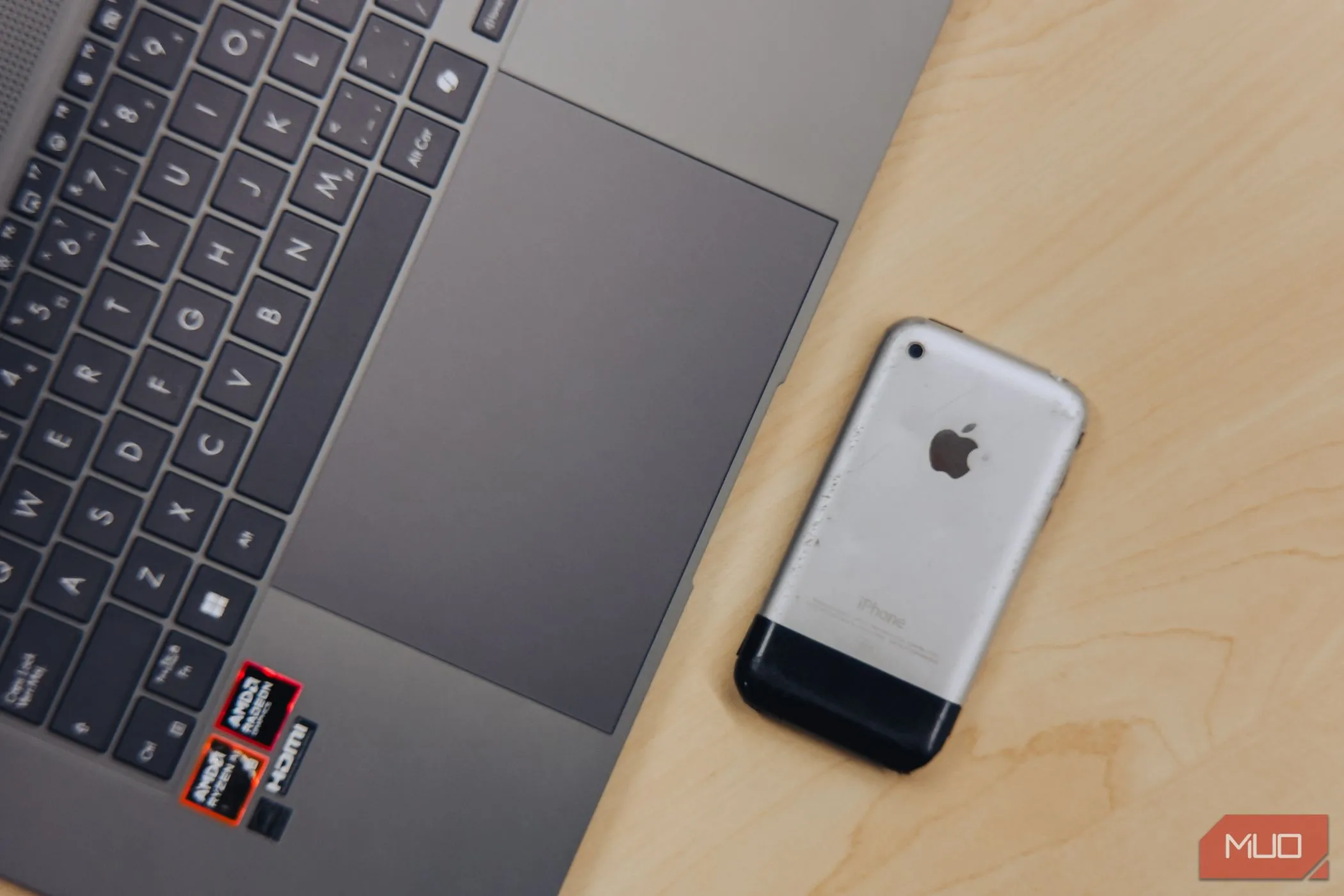 Cận cảnh trackpad lớn của ASUS Zenbook S 16 OLED đặt cạnh iPhone 2G