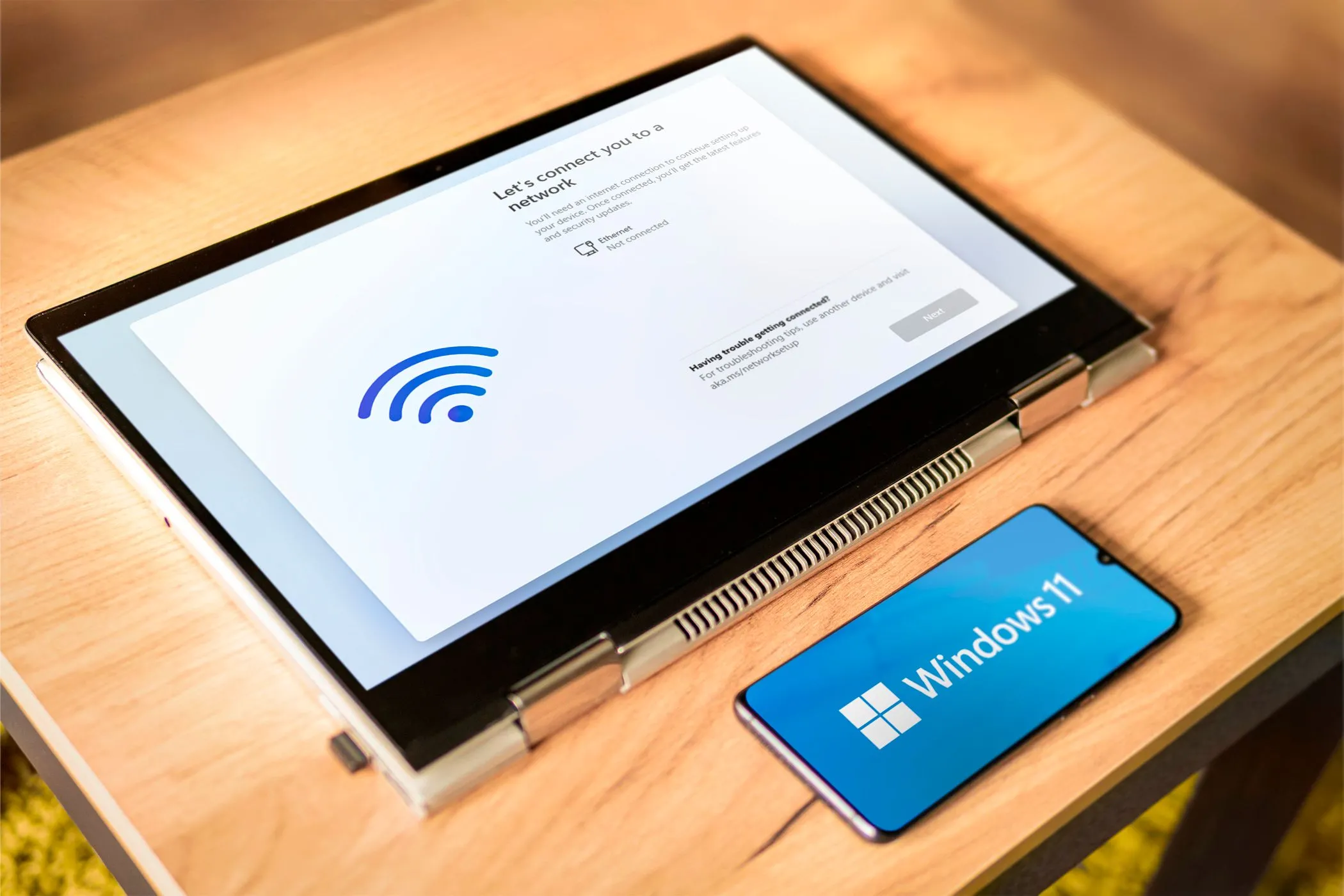 Điện thoại Android hiển thị logo Windows 11 bên cạnh laptop, minh họa việc sử dụng điện thoại làm màn hình phụ.