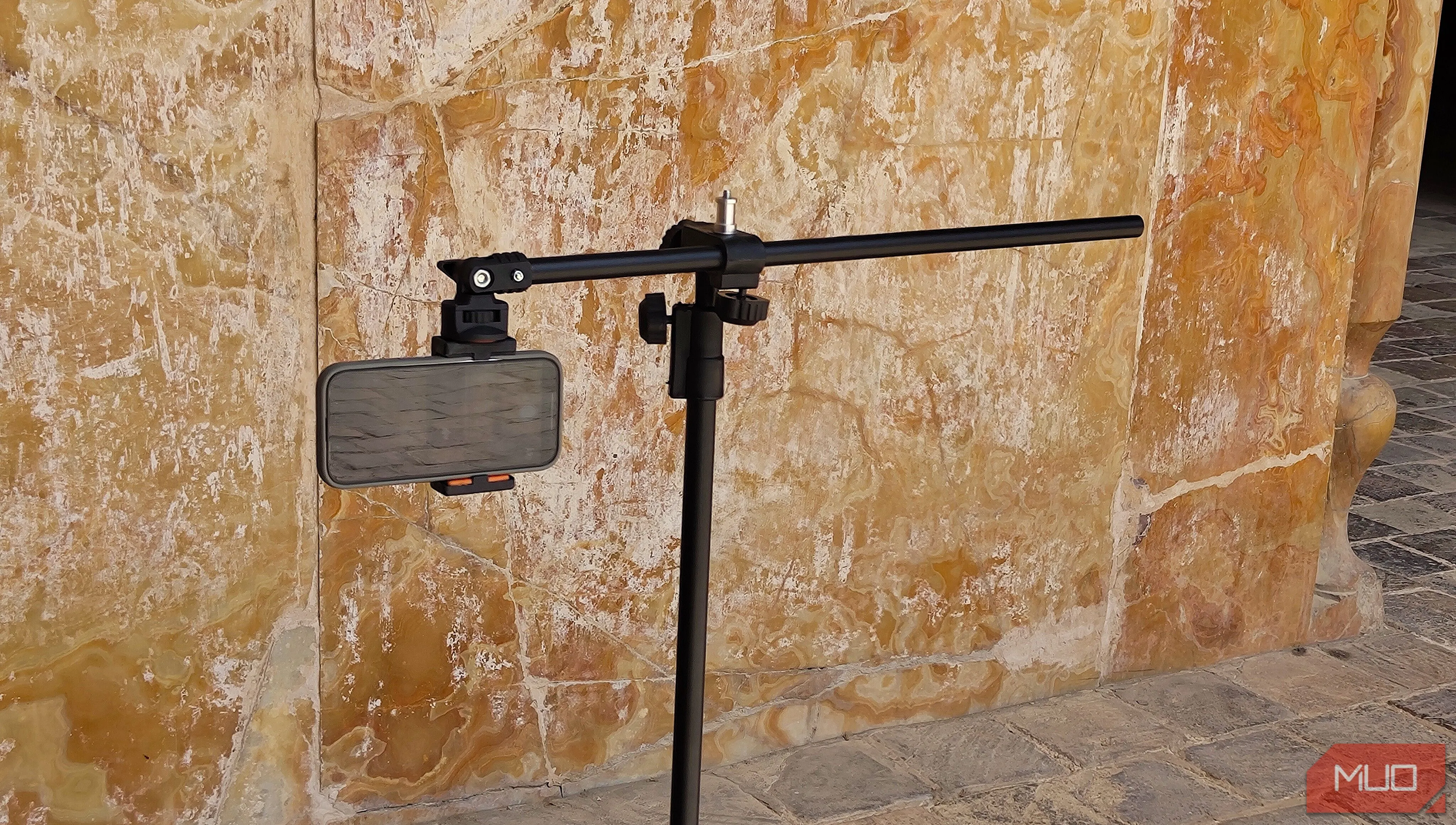Điện thoại được gắn trên tripod, hướng về một bức tường cao để minh họa cách chụp panorama dọc các kiến trúc ấn tượng