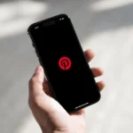 Điện thoại hiển thị giao diện Dark Mode của Pinterest trên màn hình OLED