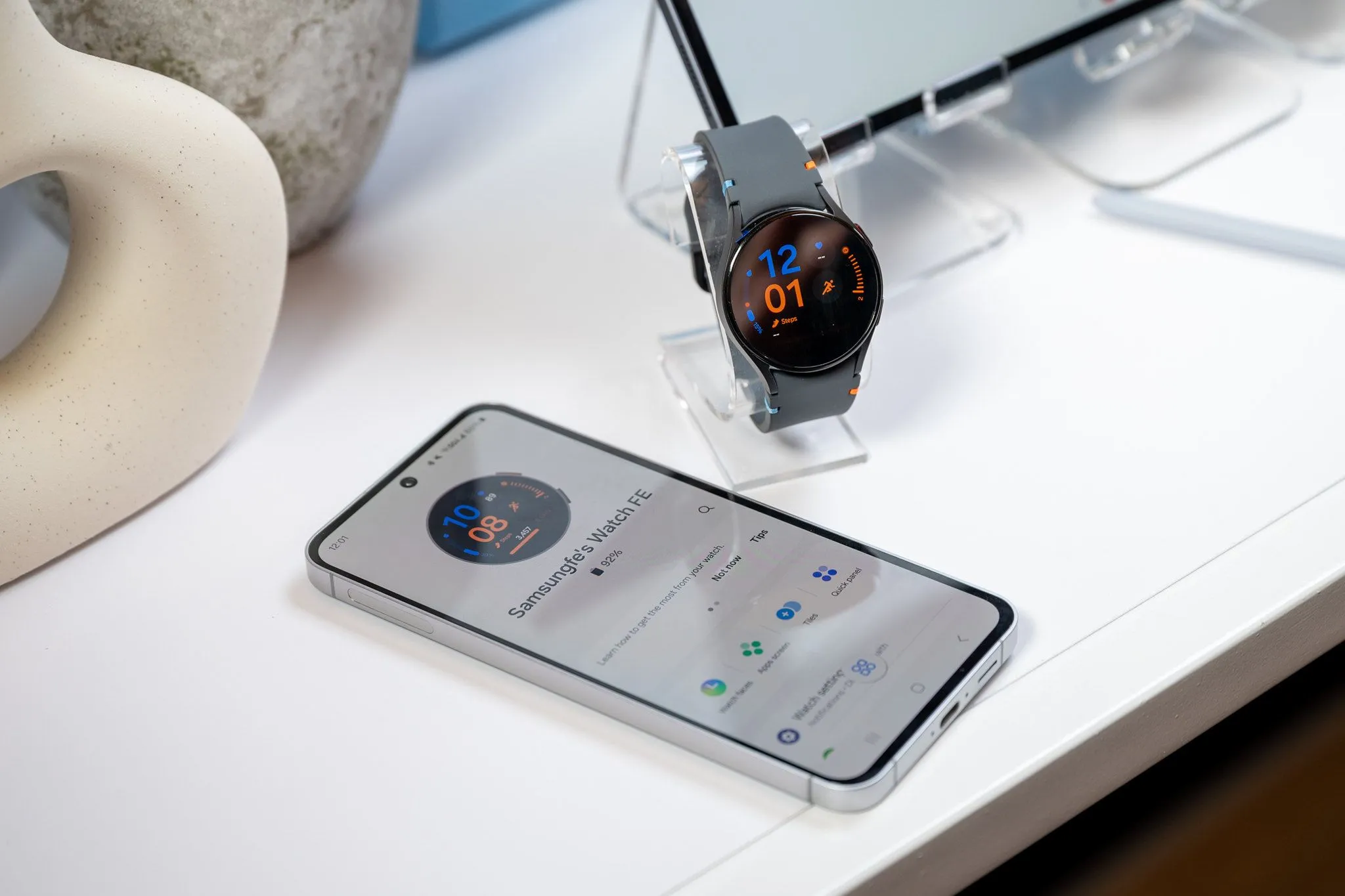 Điện thoại Samsung Galaxy S24 FE kết nối với đồng hồ Galaxy Watch LTE qua cáp USB-C, minh họa tính năng sạc ngược cho thiết bị đeo.
