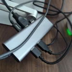 Dock USB-C thông thường với nhiều cáp kết nối, trông lộn xộn trên bàn làm việc, minh họa sự thiếu gọn gàng.