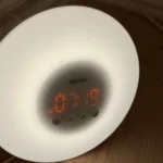 Đồng hồ báo thức mặt trời mọc với ánh sáng giả lập bình minh trên mặt sàn gỗ, giúp người dùng thức dậy tự nhiên hơn.