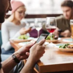 Du khách sử dụng điện thoại để tìm Wi-Fi miễn phí tại quán cà phê