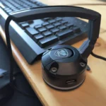 Giá đỡ dây chuột (mouse bungee) màu đen đặt trên bàn gỗ