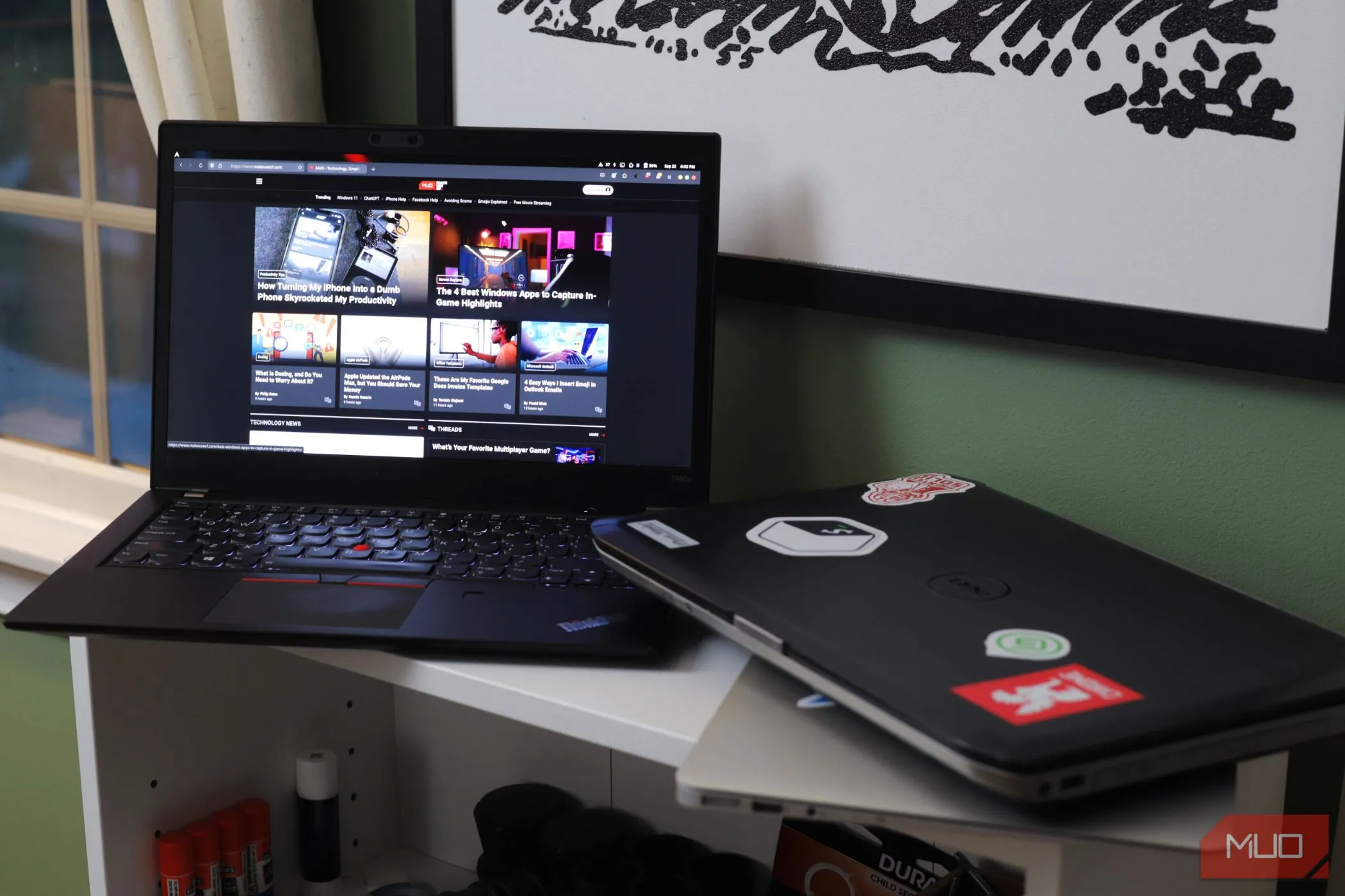 Hai chiếc laptop trên kệ, một chiếc đang mở màn hình, tượng trưng cho rủi ro bảo mật khi chia sẻ thiết bị.