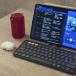 Hình ảnh iPad Air M1 cùng bàn phím Logitech Pebble Keys 2 K380s và tai nghe AirPods trên bàn làm việc, minh họa thiết lập làm việc gọn nhẹ với iPad.