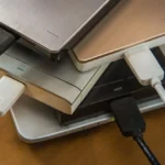 Hình ảnh nhiều ổ đĩa cứng ngoài đặt trên laptop, minh họa sự phức tạp và lộn xộn khi quản lý nhiều thiết bị lưu trữ, dù là phân vùng hay ổ vật lý riêng biệt.