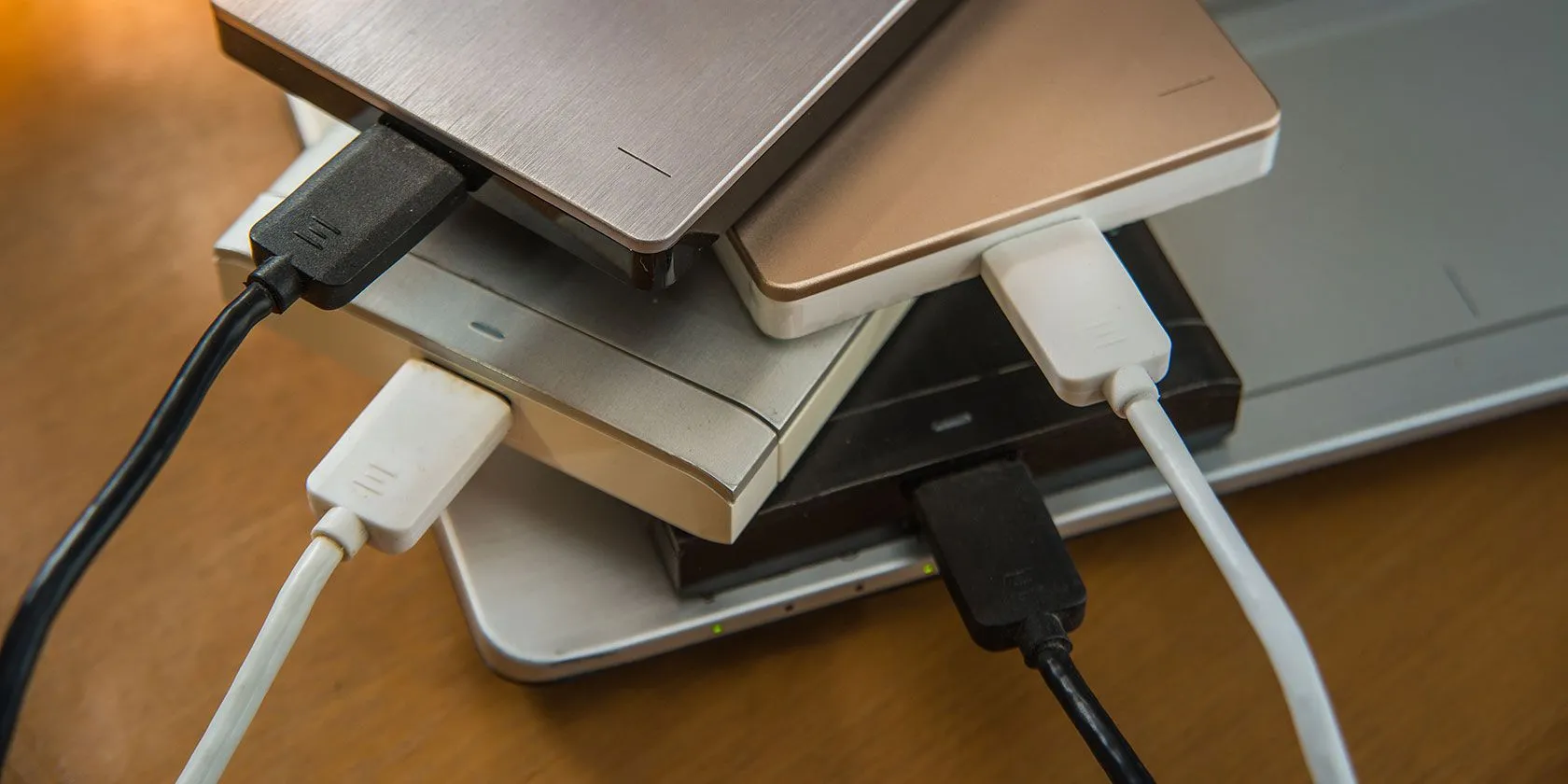 Hình ảnh nhiều ổ đĩa cứng ngoài đặt trên laptop, minh họa sự phức tạp và lộn xộn khi quản lý nhiều thiết bị lưu trữ, dù là phân vùng hay ổ vật lý riêng biệt.
