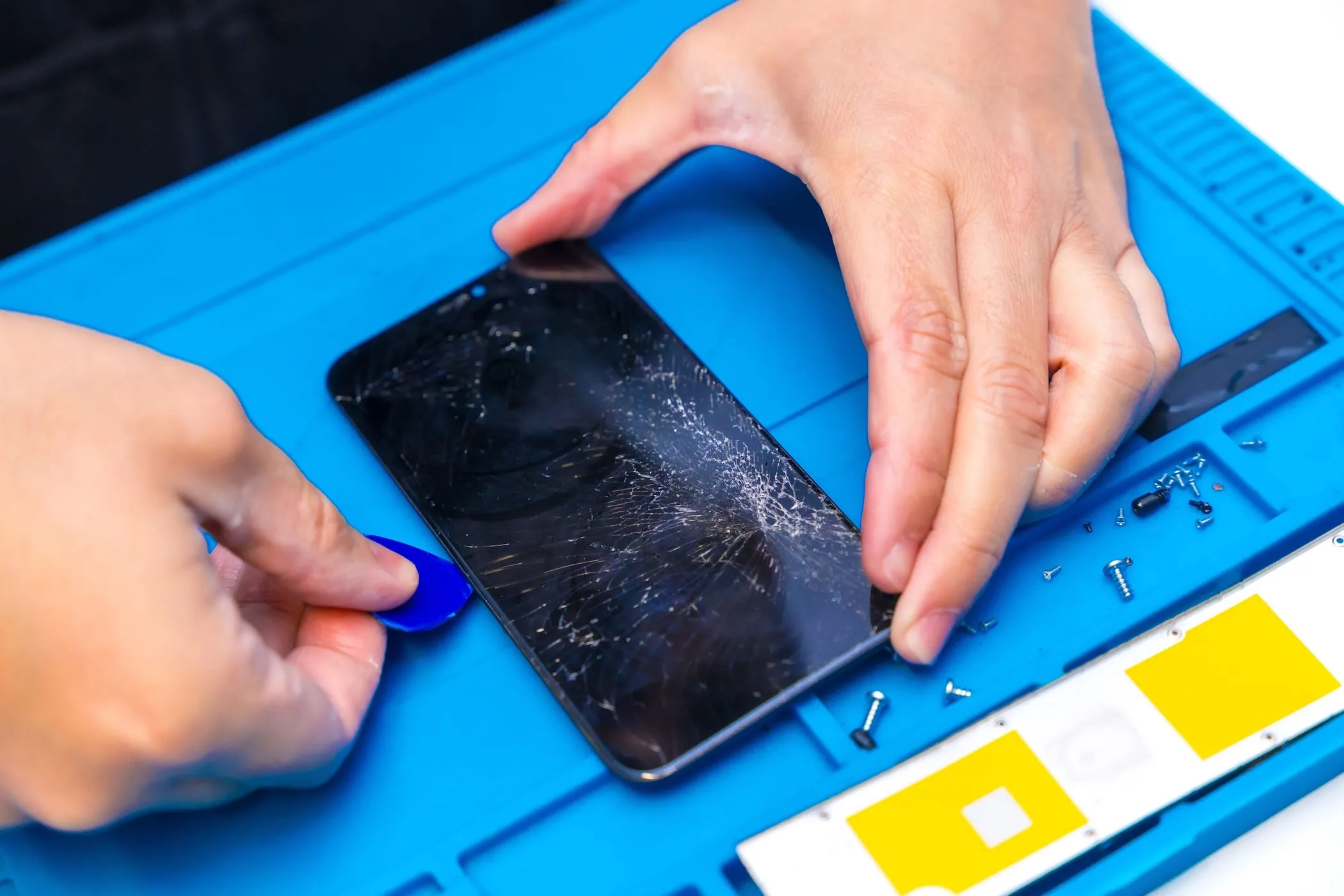 Kỹ thuật viên đang cẩn thận cạy mở smartphone để sửa chữa, minh họa quy trình bảo trì chuyên nghiệp