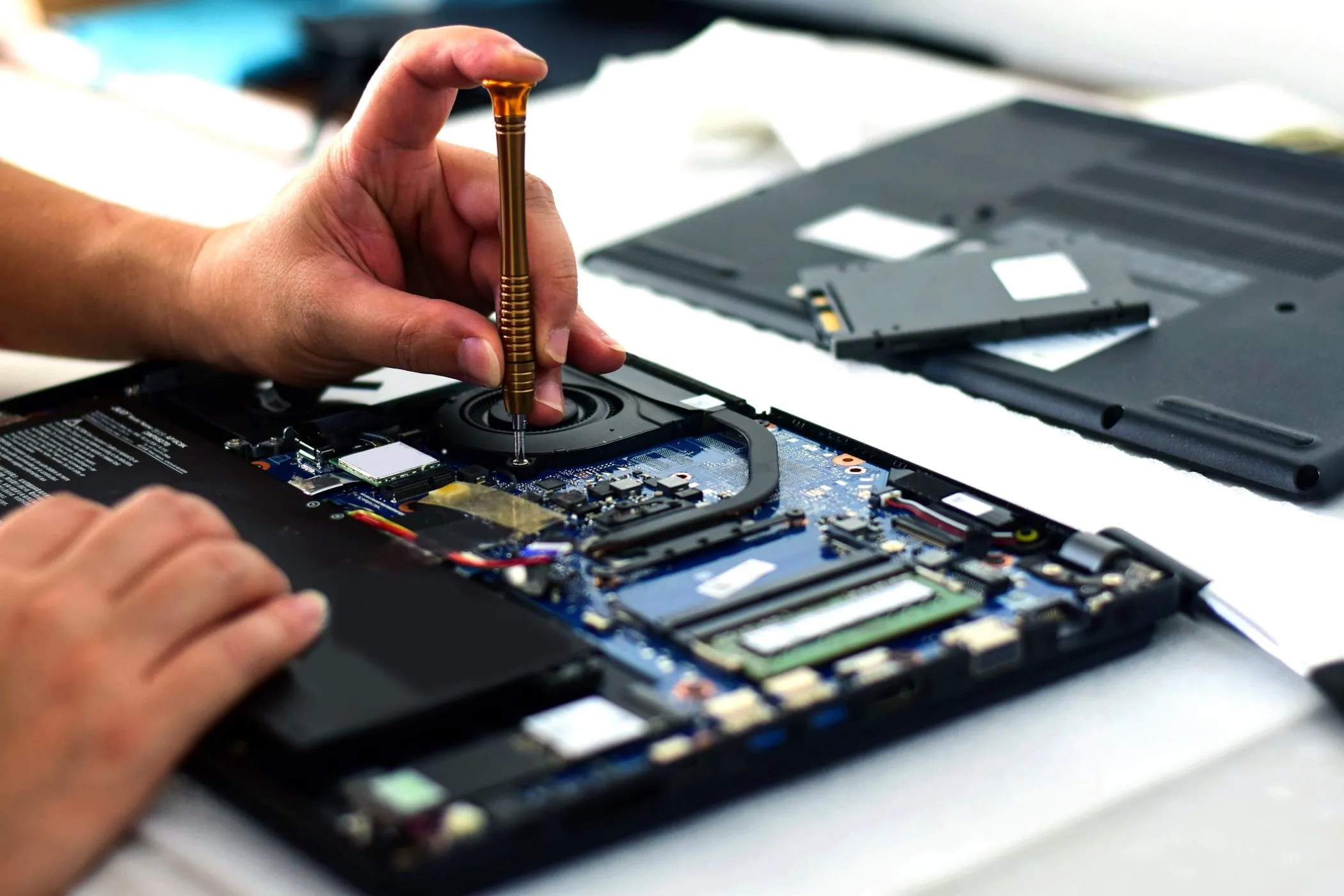 Kỹ thuật viên đang sử dụng tua vít để sửa chữa bo mạch chủ laptop, minh họa sự phức tạp khi sửa laptop mỏng nhẹ