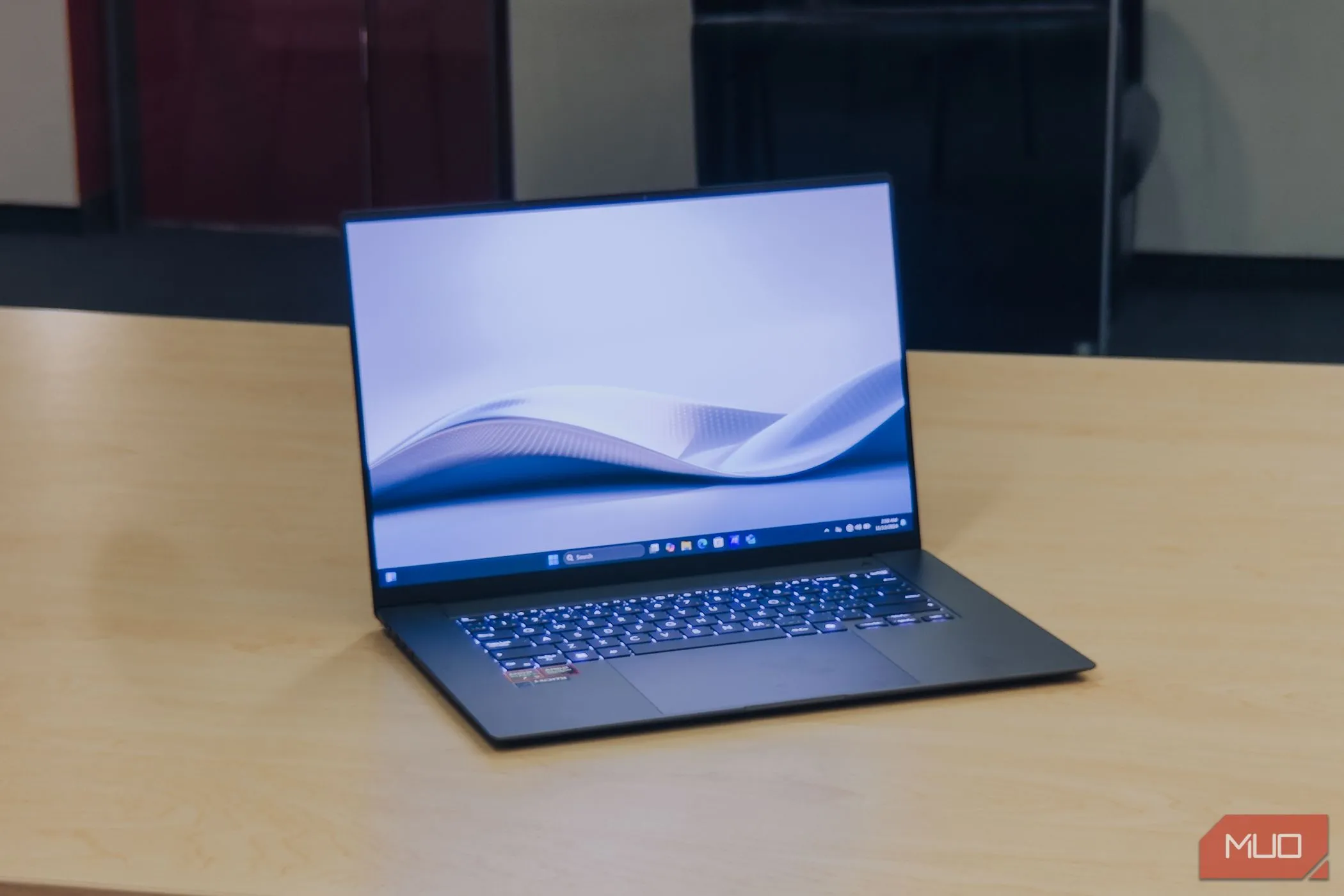 Laptop ASUS Zenbook S 16 OLED màu trắng đặt nghiêng trên bàn gỗ, màn hình hiển thị nội dung