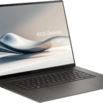 Laptop ASUS Zenbook S 16 OLED màu trắng trên nền gỗ và đá