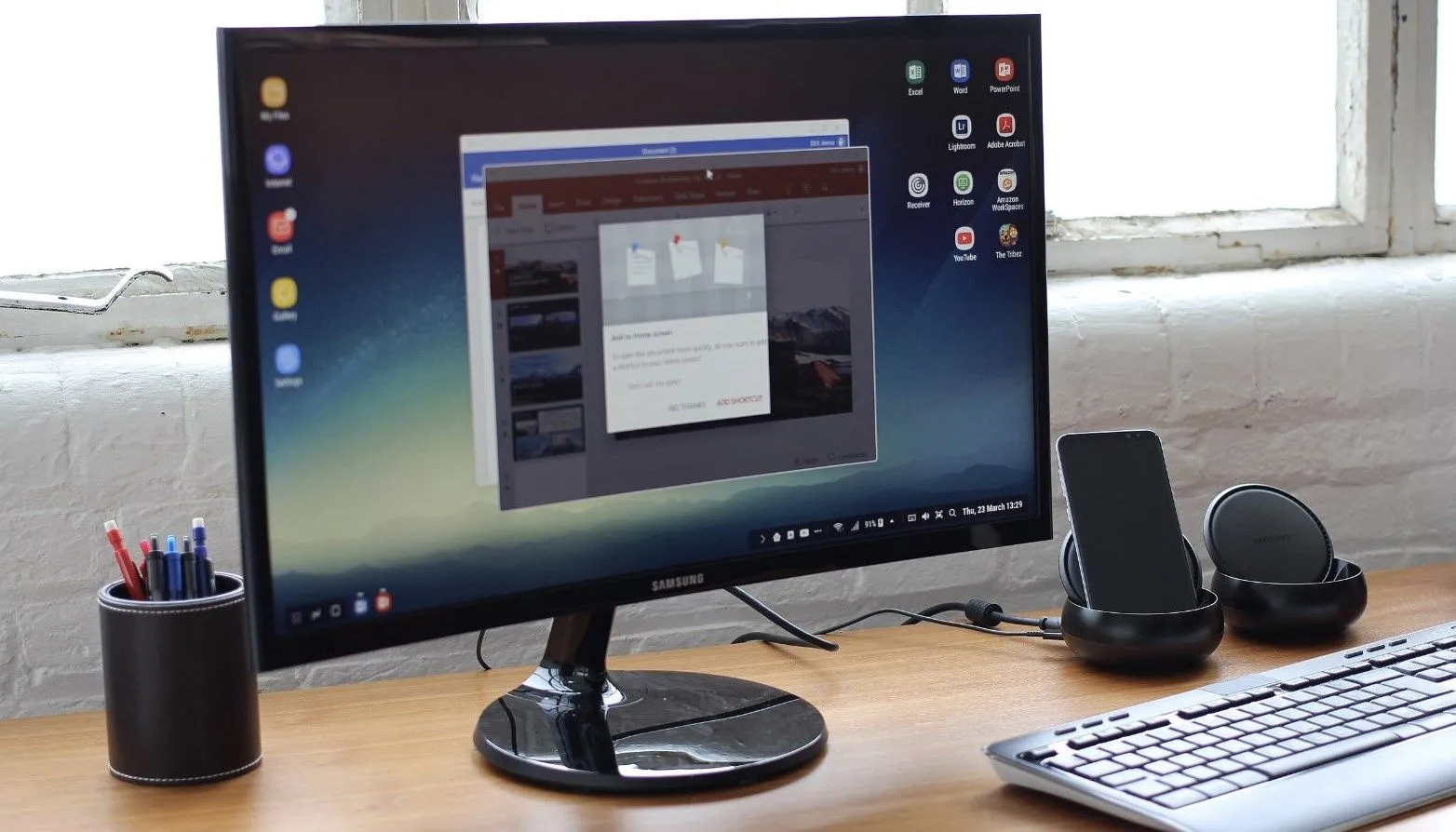 Màn hình Samsung hiển thị giao diện Samsung DeX kết nối với điện thoại Galaxy và phụ kiện bàn phím, chuột để làm việc