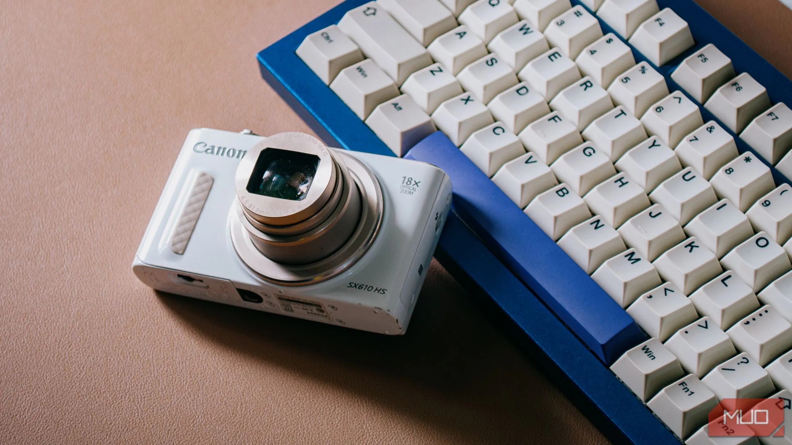Máy ảnh digicam nhỏ gọn với ống kính đã mở, đặt trên bàn phím máy tính, thể hiện sự sẵn sàng cho mọi khoảnh khắc nhiếp ảnh