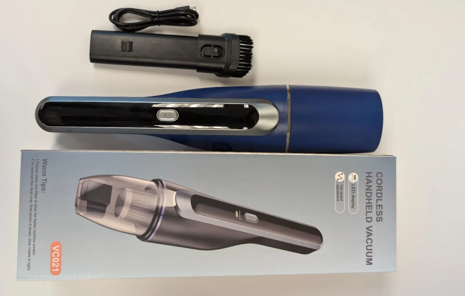 Máy hút bụi cầm tay không dây màu xanh dương cùng các phụ kiện đi kèm, sạc qua cổng USB.
