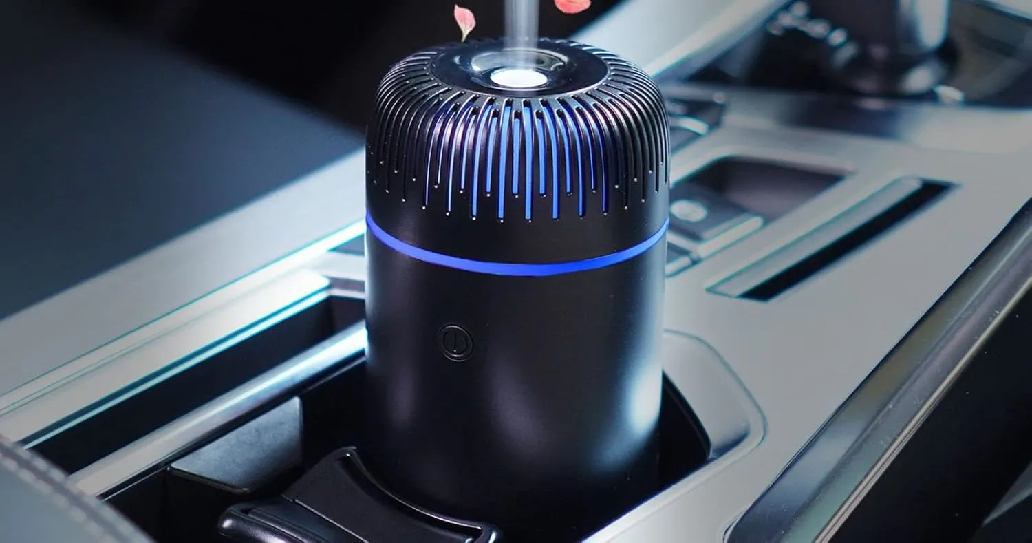 Máy khuếch tán tinh dầu hoặc tạo độ ẩm mini hình trụ đặt gọn gàng trong khay đựng cốc trên ô tô.