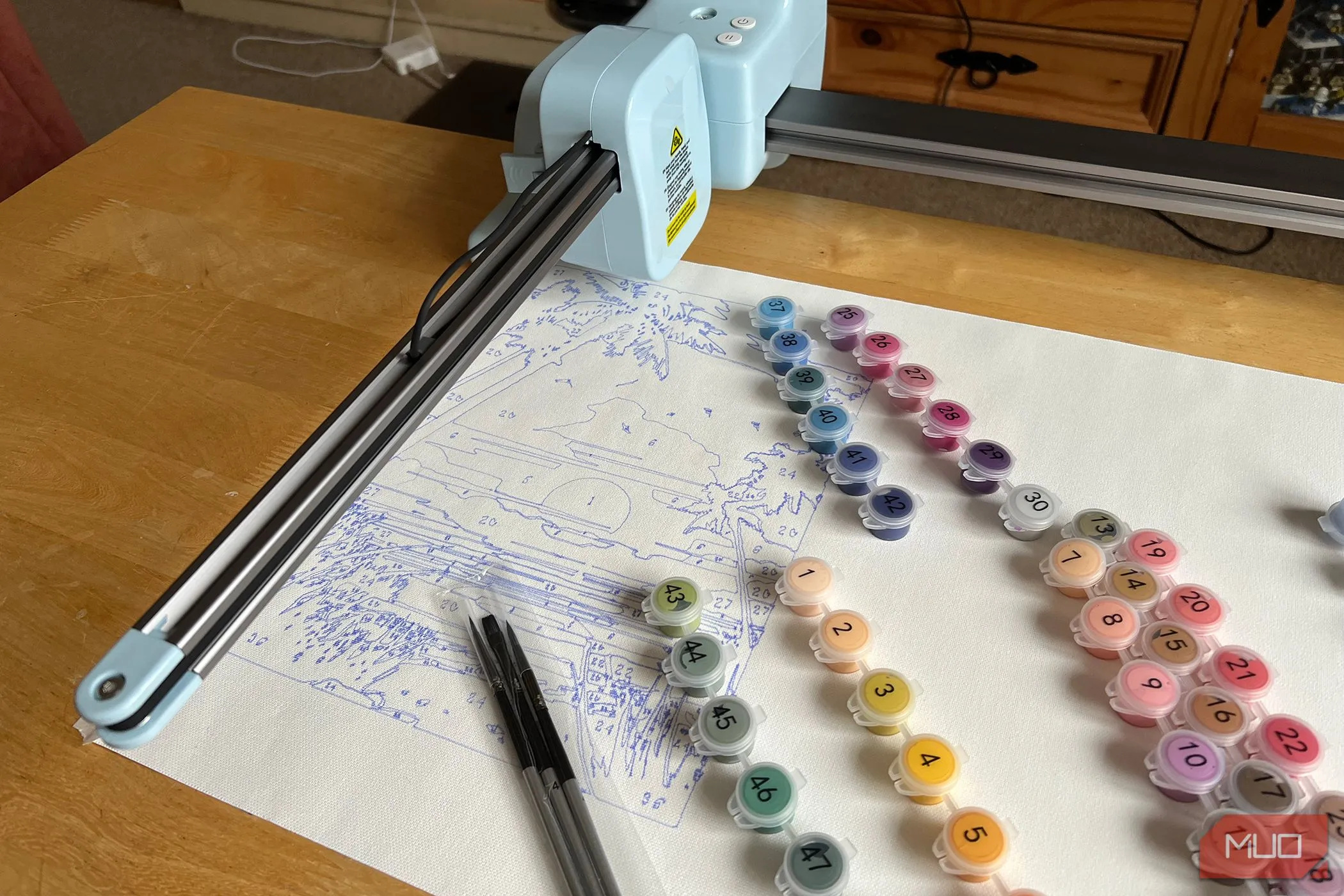 Máy LOKLiK iPaint đang vẽ cảnh hoàng hôn với các hộp màu được đặt cạnh bên