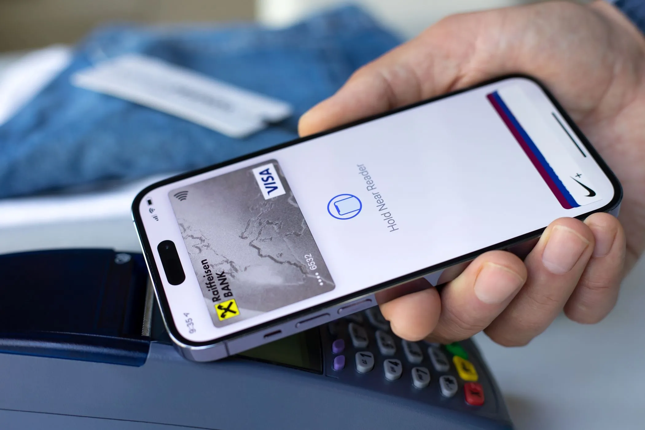 Một người đàn ông thanh toán bằng Apple Pay trên iPhone tại cửa hàng, minh họa giao dịch số và rủi ro dữ liệu cá nhân.