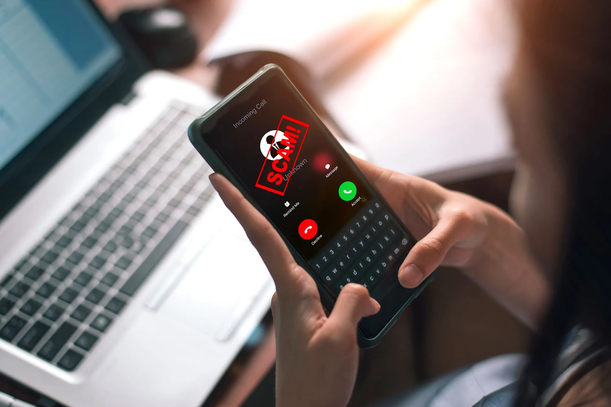 Một người phụ nữ đang trả lời cuộc gọi điện thoại thông minh với cảnh báo lừa đảo hiển thị trên màn hình