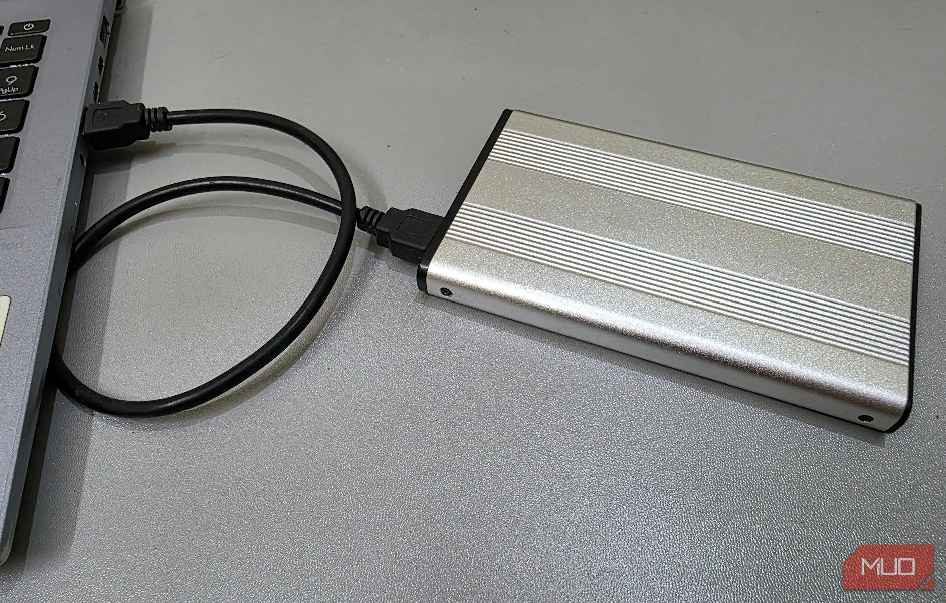 Một ổ cứng ngoài được kết nối với laptop qua cáp, minh họa việc sử dụng thiết bị để bảo mật dữ liệu nhạy cảm.