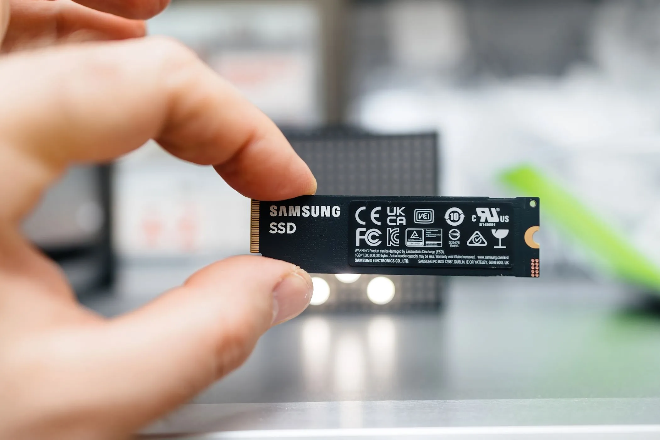 Một ổ cứng SSD Samsung kích thước nhỏ gọn được giữ giữa hai ngón tay, biểu tượng cho sự tiện lợi và giá thành phải chăng của các ổ đĩa thể rắn dung lượng cao hiện nay.