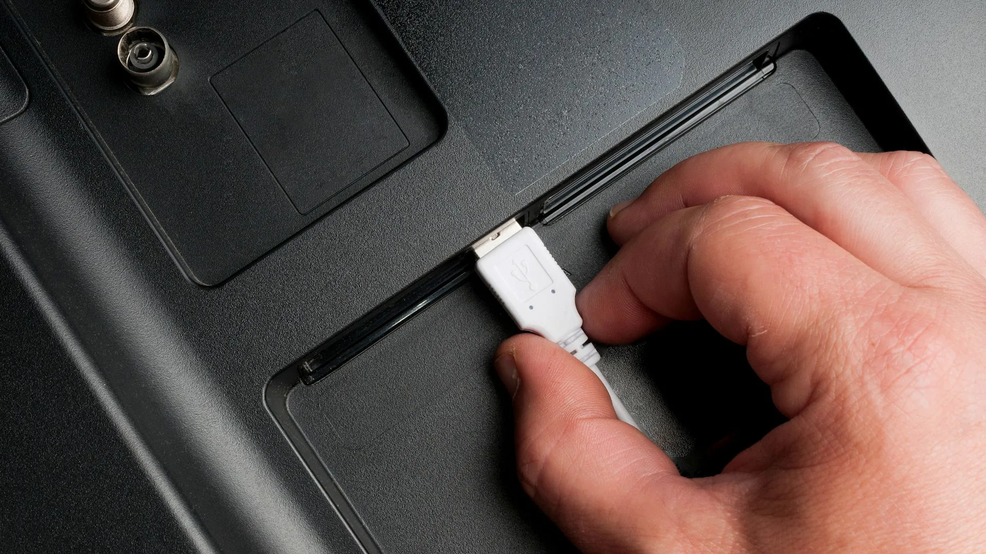Người đàn ông cắm cáp USB-A vào cổng TV, minh họa sự đa dạng cổng sạc