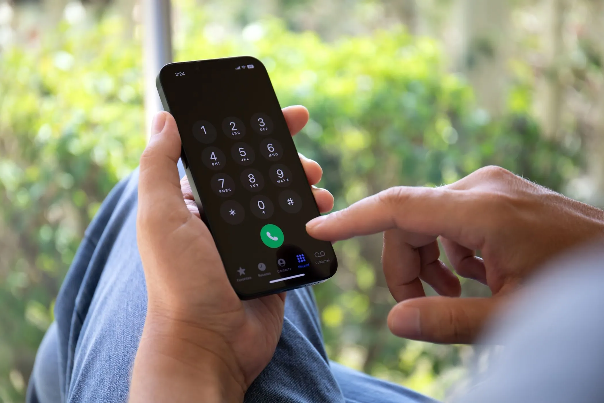 Người đàn ông đang cố gắng nhập số điện thoại trên iPhone, thể hiện sự phụ thuộc của SMS 2FA vào tín hiệu di động