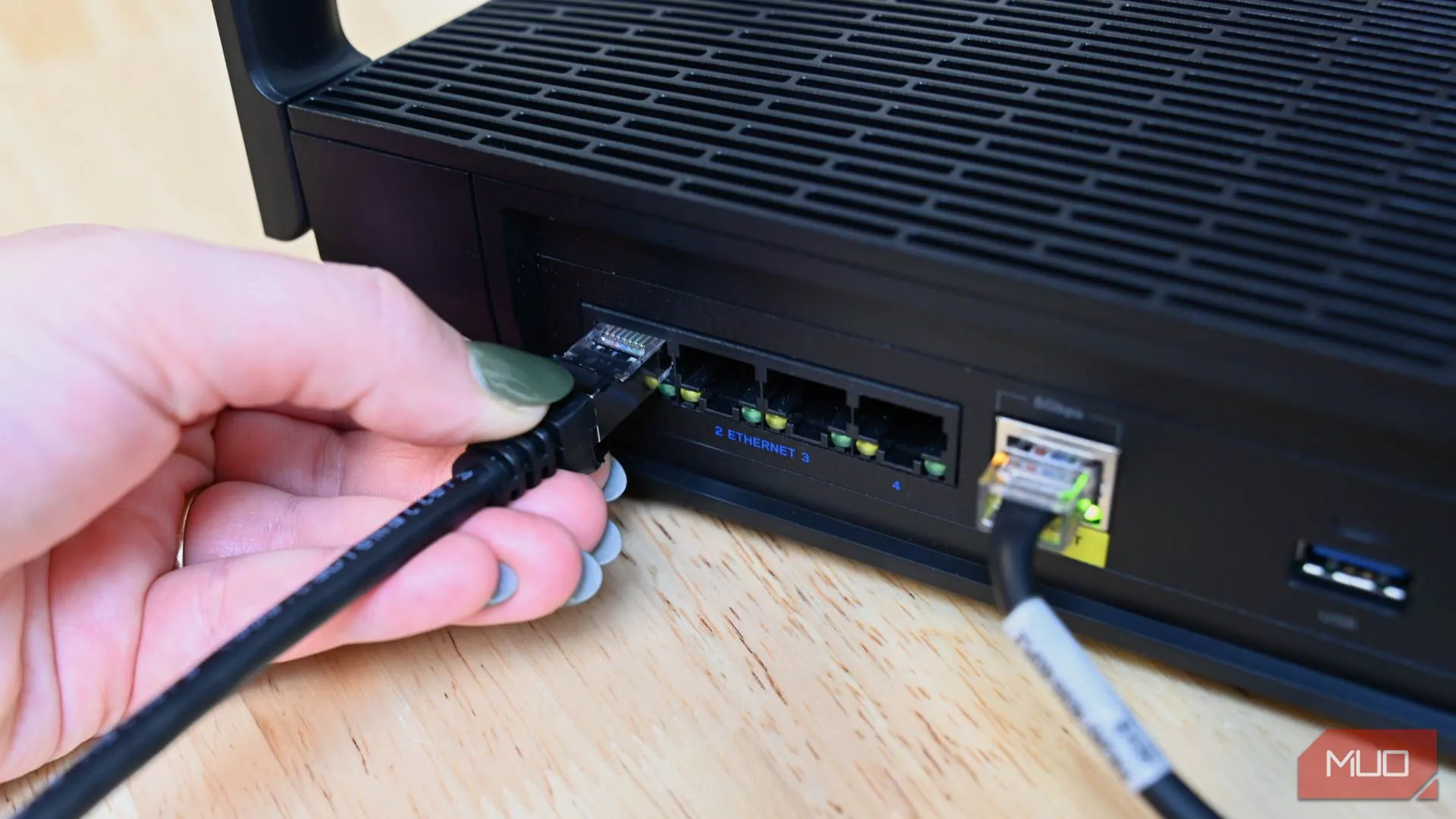 Người dùng cắm cáp Ethernet vào router, minh họa việc sử dụng kết nối mạng có dây để đạt tốc độ internet ổn định và nhanh hơn
