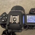 Người dùng điều chỉnh cài đặt trên màn hình LCD của máy ảnh mirrorless, thể hiện giao diện phức tạp và tính năng cao cấp của dòng máy này.