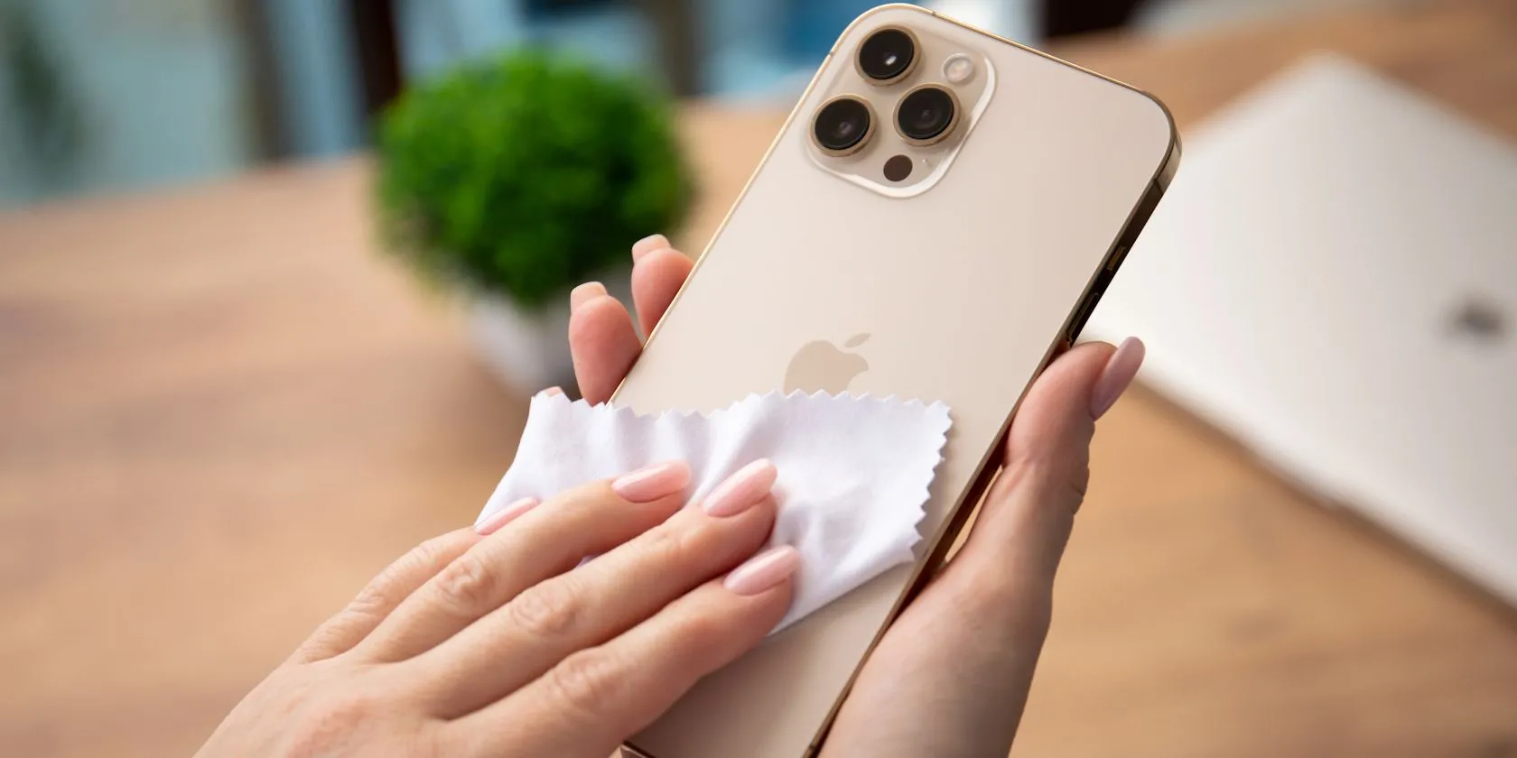 Người phụ nữ đang vệ sinh màn hình iPhone bằng khăn microfiber, phương pháp hiệu quả hơn bộ vệ sinh cao cấp