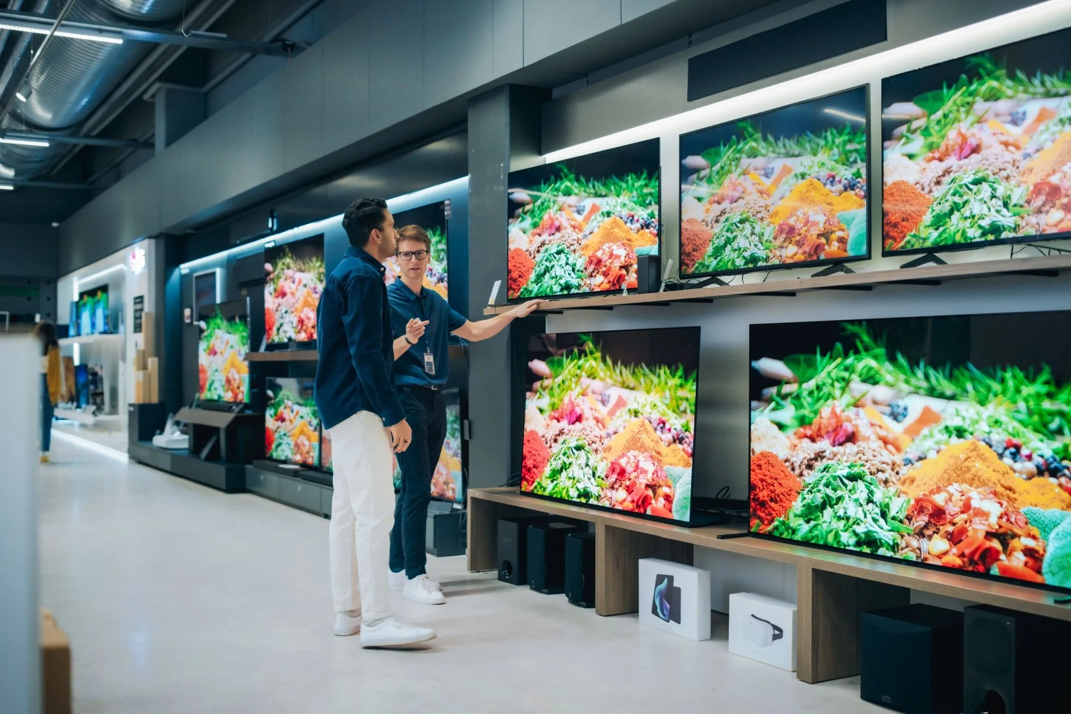 Nhân viên cửa hàng tư vấn khách hàng xem TV, thể hiện trải nghiệm mua sắm cá nhân hóa và các ưu đãi độc quyền từ thẻ thành viên.