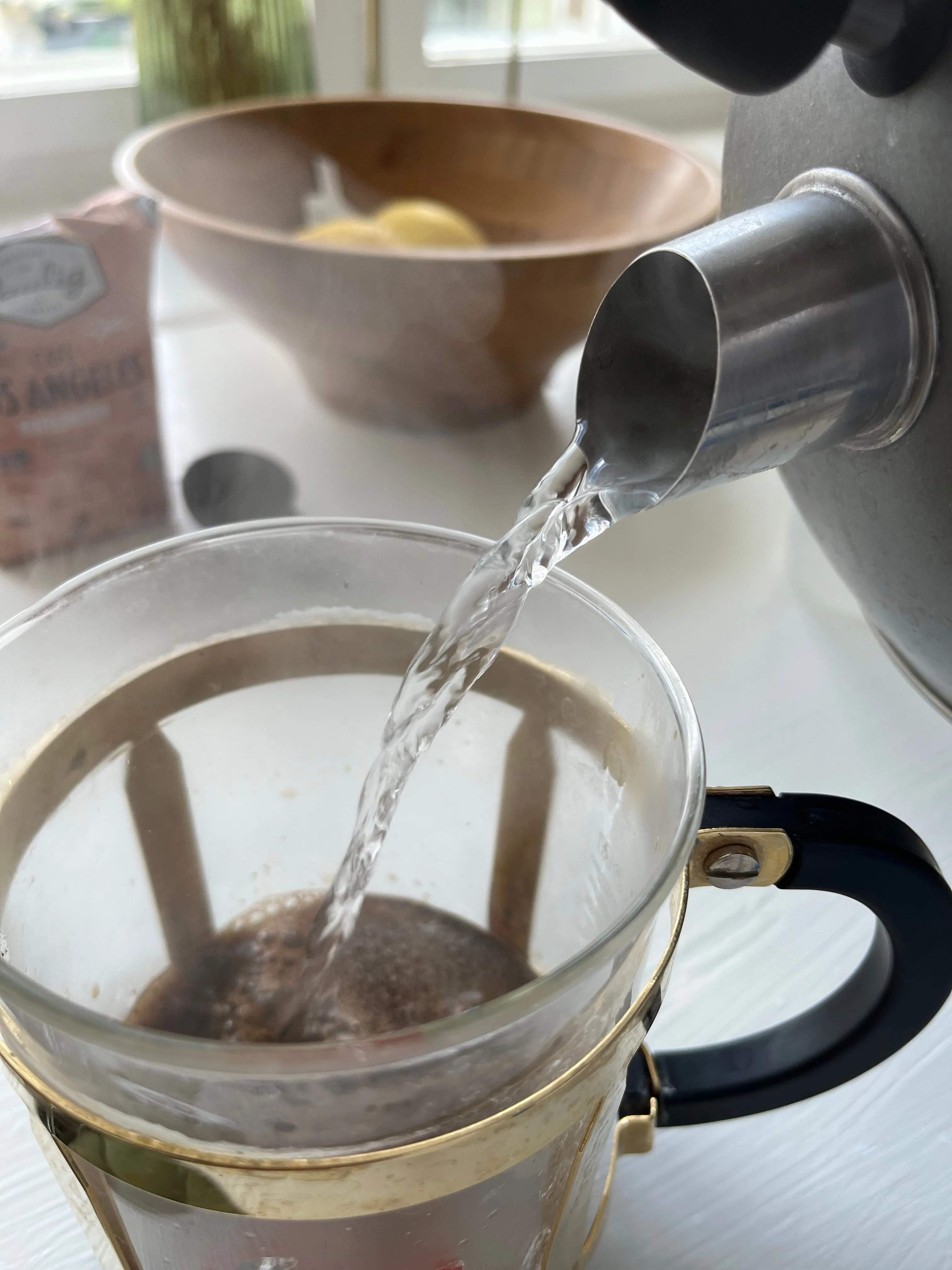 Nước sôi được rót từ ấm vào bình pha cà phê kiểu French press, ghi lại chi tiết quá trình pha chế đồ uống hàng ngày.