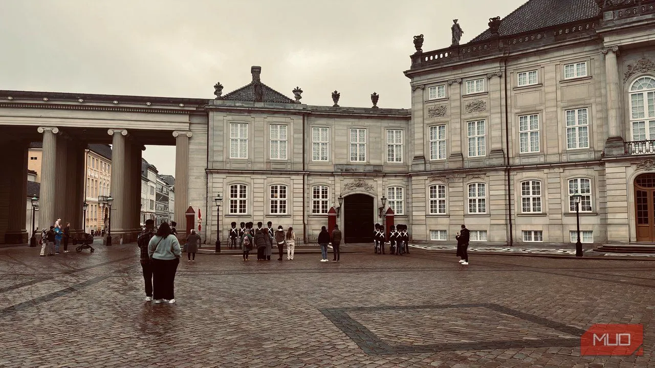 Quảng trường Cung điện Amalienborg với đội quân đang diễu hành dưới trời mưa, thể hiện hoạt động thường nhật và không gian lịch sử.