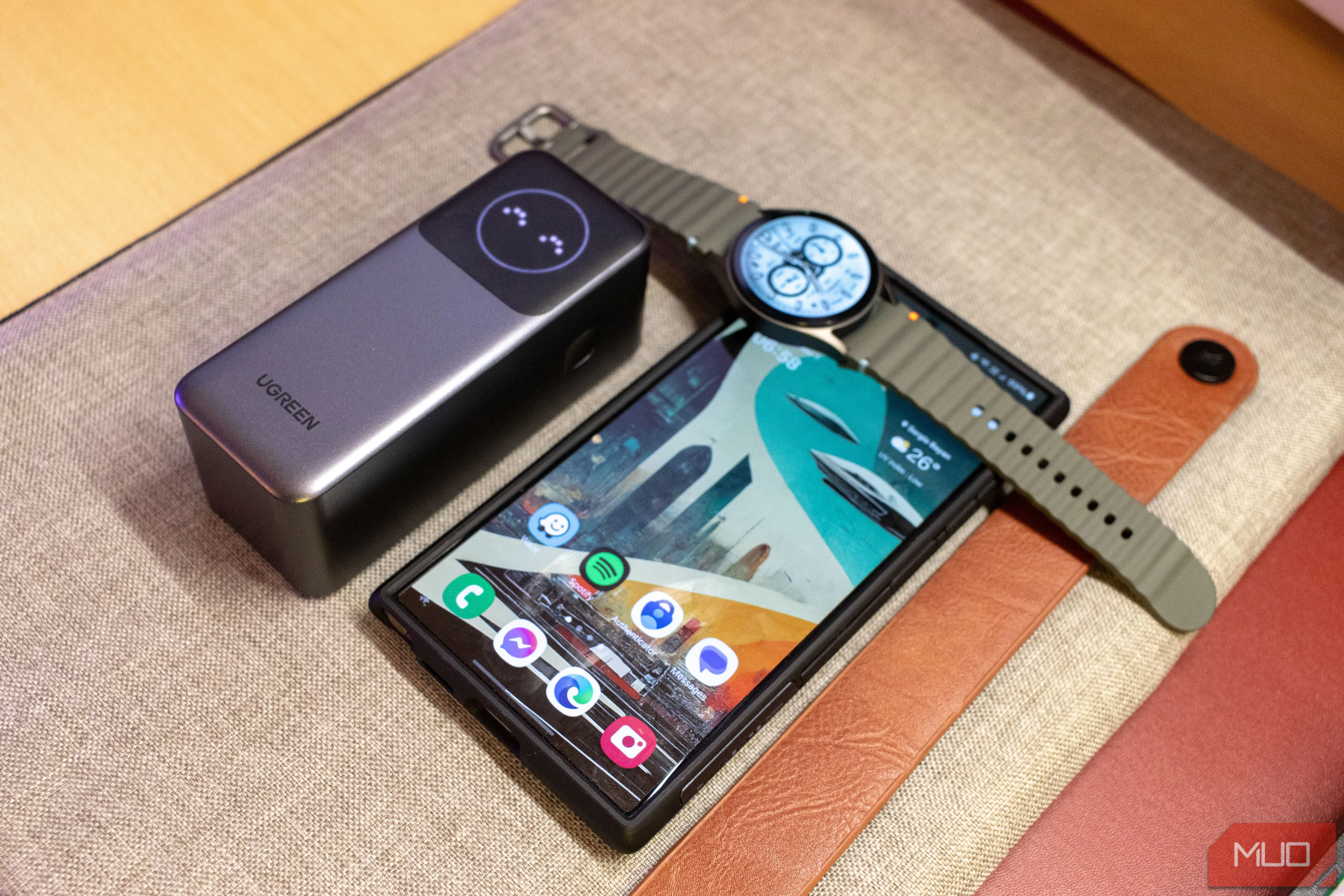 Sạc dự phòng Ugreen Nexode 12000mAh bên cạnh Samsung S24 Ultra và Galaxy Watch7, minh họa khả năng sạc đa thiết bị.