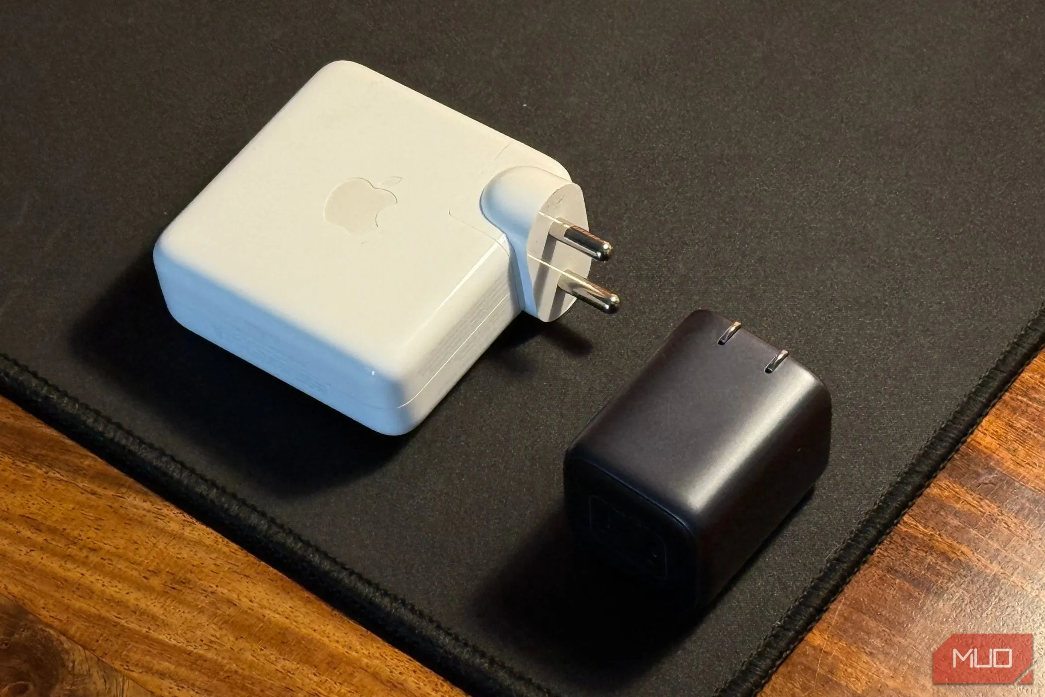 So sánh kích thước giữa củ sạc iPhone nhỏ gọn và bộ chuyển đổi nguồn MacBook, nhấn mạnh sự đa dạng phụ kiện.