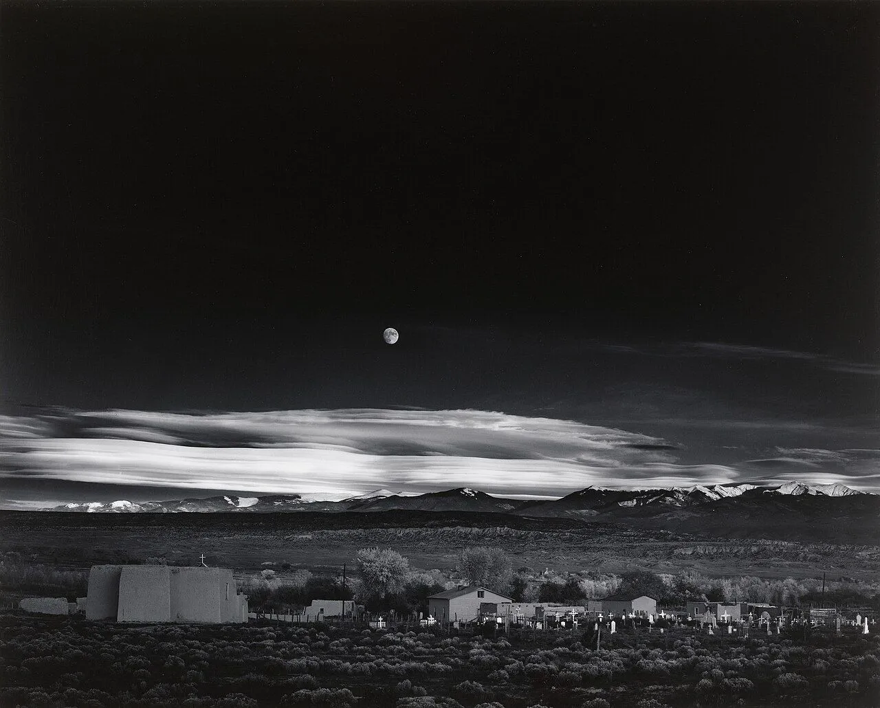 Tác phẩm &quot;Moonrise, Hernandez, New Mexico&quot; của Ansel Adams, một bức ảnh phong cảnh đen trắng nổi tiếng với kỹ thuật tương phản bậc thầy.