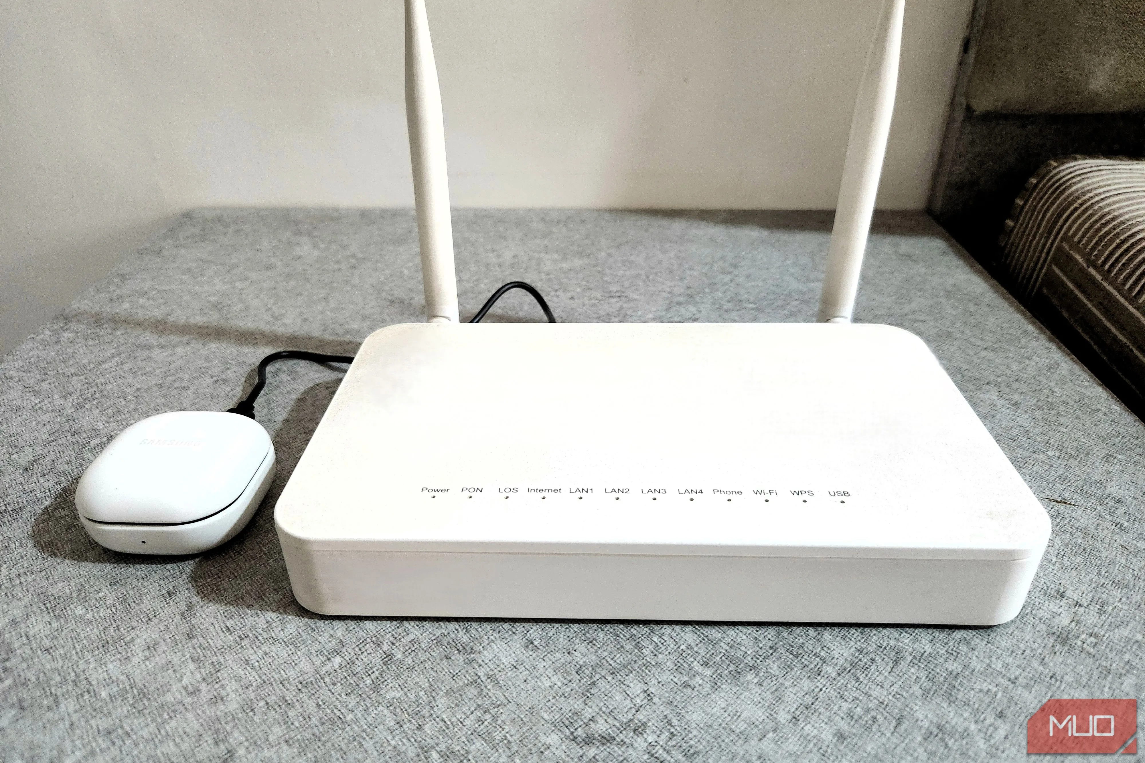 Tai nghe Bluetooth đang sạc qua cổng USB của router Wi-Fi